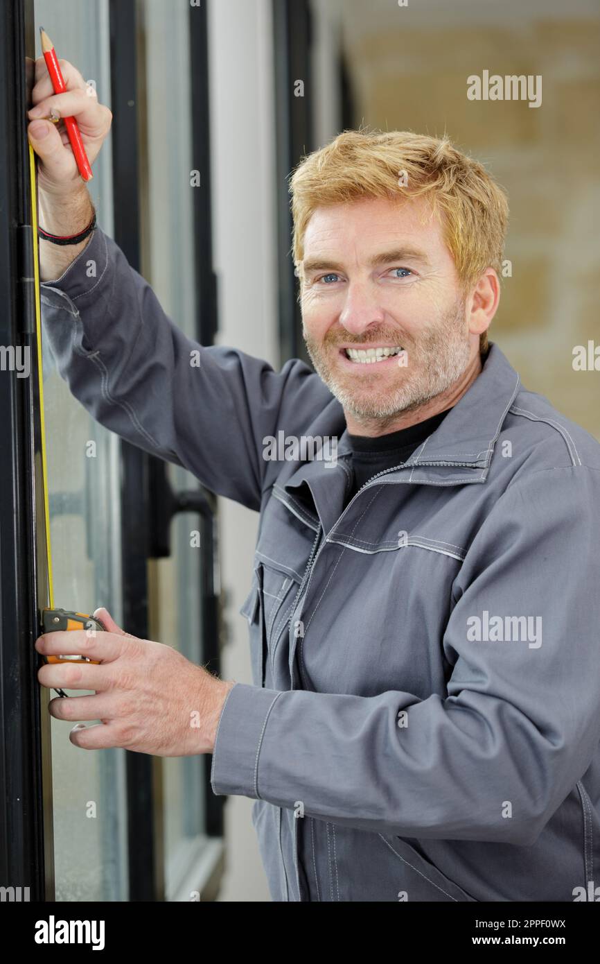 man measuring window prior to installation Stock Photo - Alamy