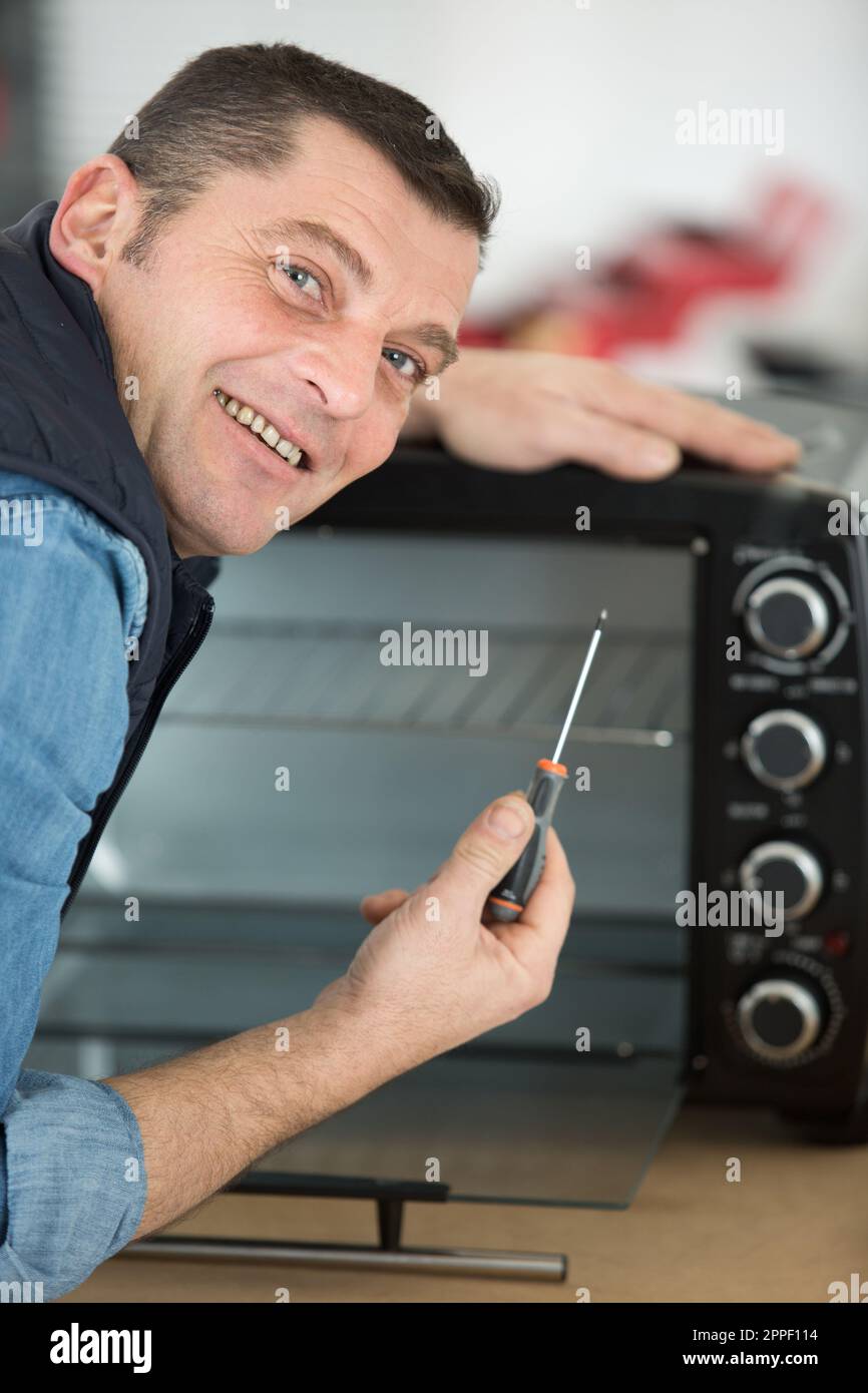 man repairing microwave oven in kitchen Stock Photo