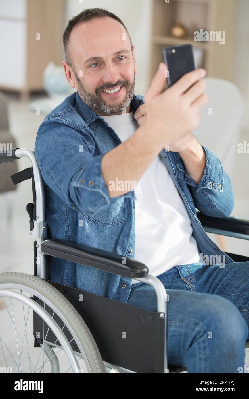 handsome man in wheelchair taking a selfie and smiles Stock Photo - Alamy