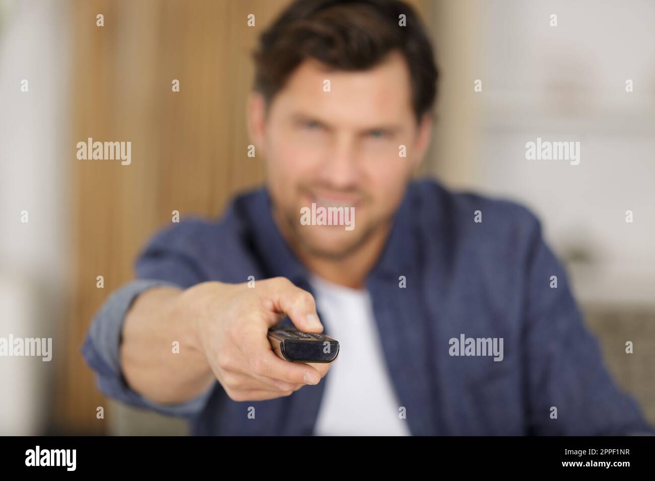 man changes the channels on the remote control Stock Photo