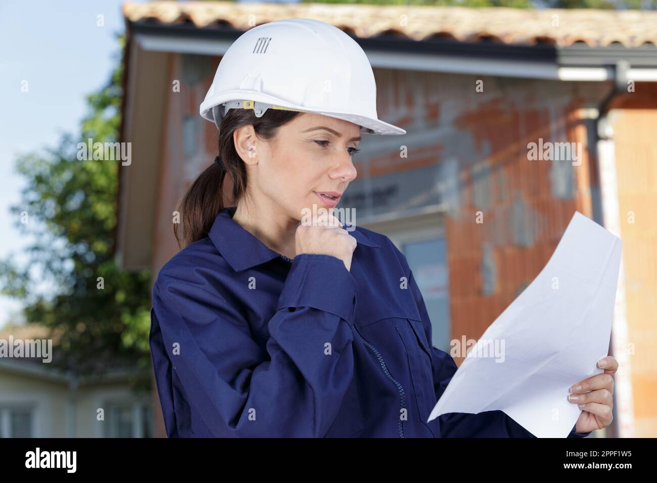 woman in building helmet looking at blueprint Stock Photo - Alamy