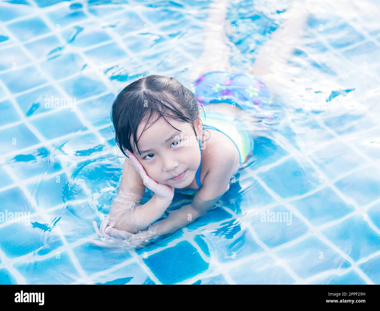 Asian girl is playing in the pool, laying down Stock Photo