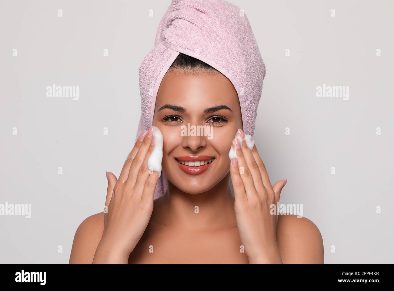 Beautiful woman applying facial cleansing foam on white background ...