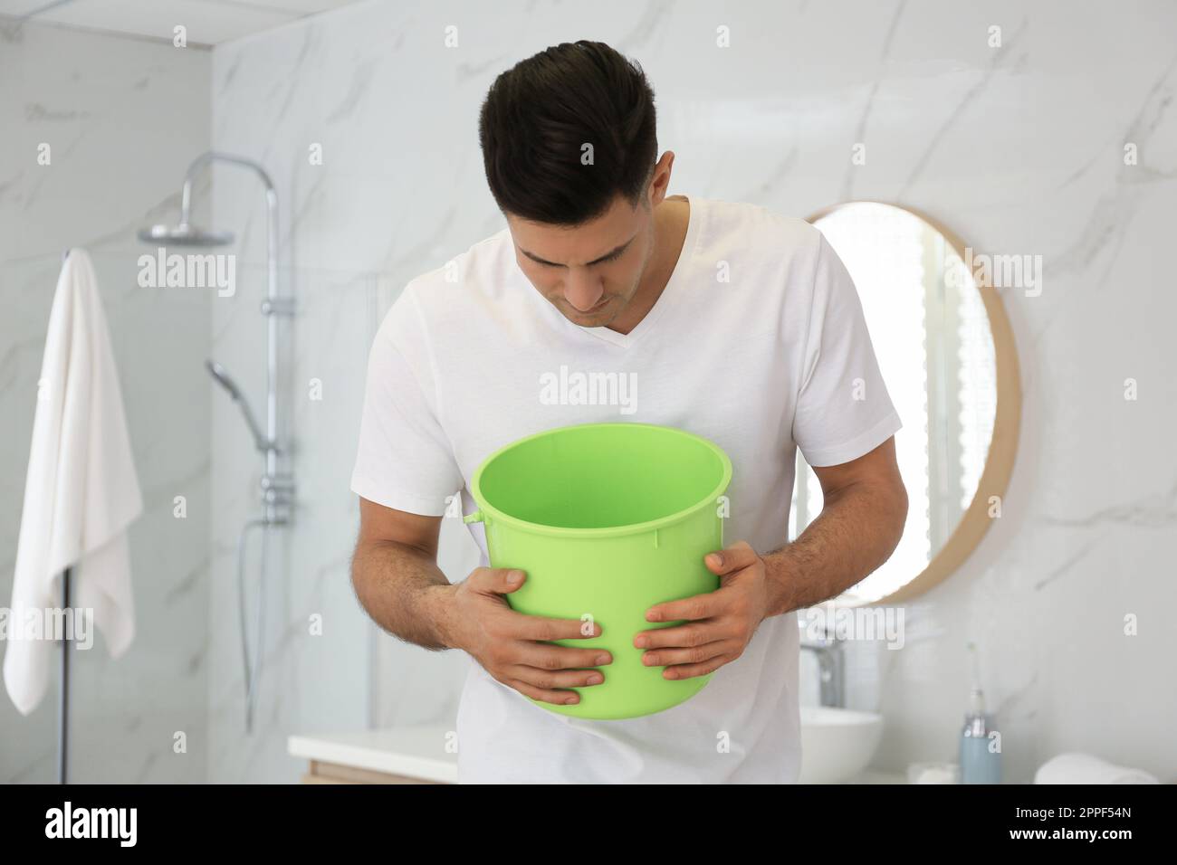Man with bucket suffering from nausea in bathroom. Food poisoning Stock ...