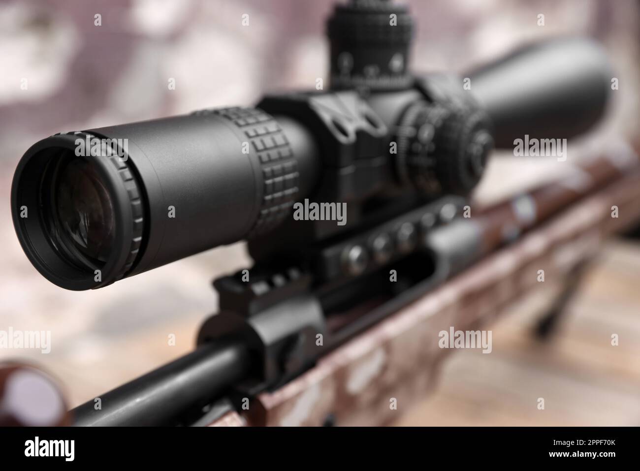 Closeup view of modern powerful sniper rifle with telescopic sight on blurred background Stock