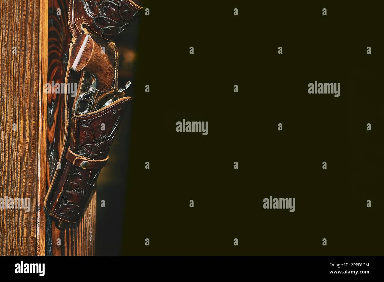 Gun pistol colt revolver in a holster on a wooden wall.Black space for