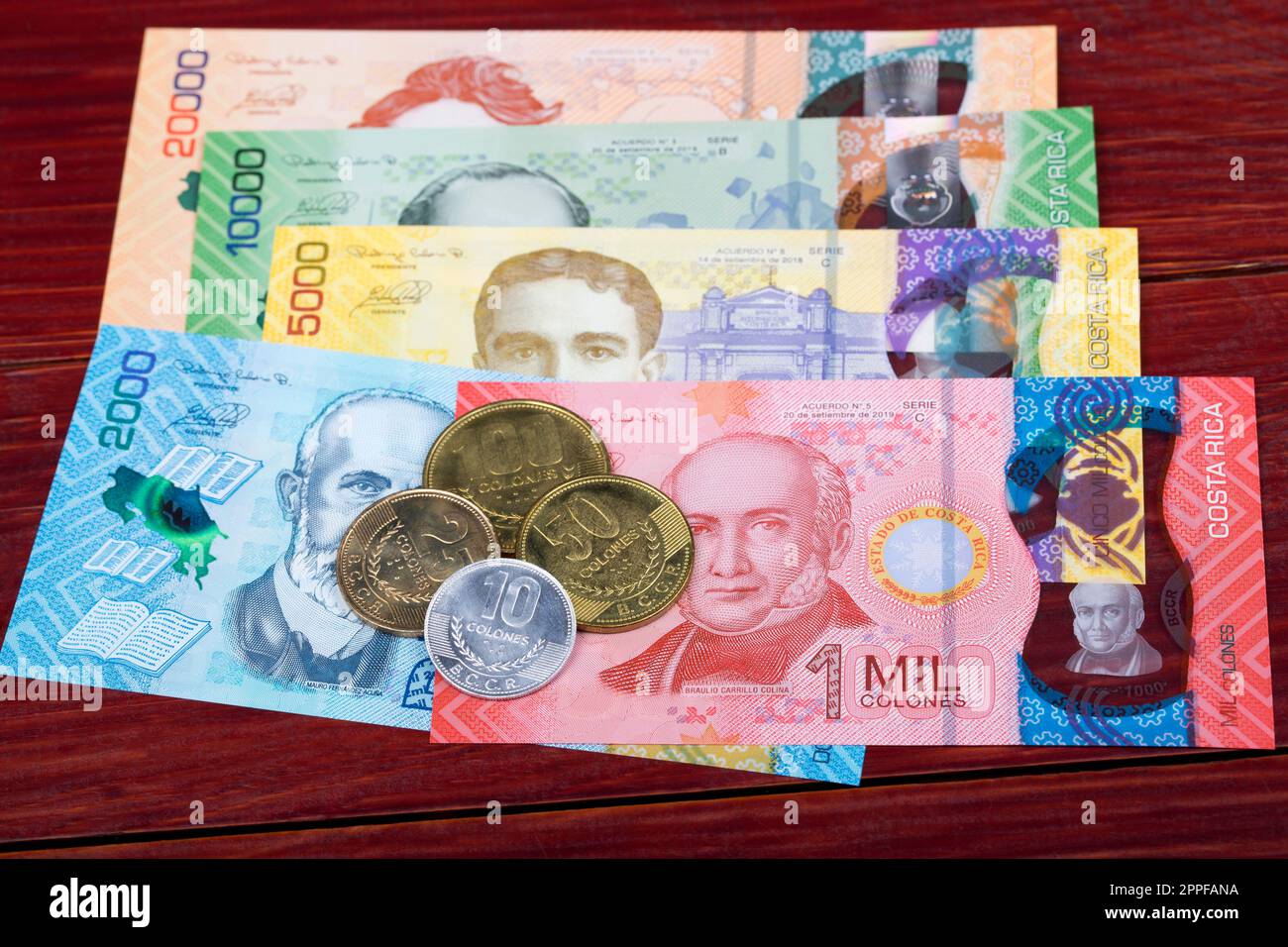 Costa Rican Colones coins and banknotes on a wooden background Stock