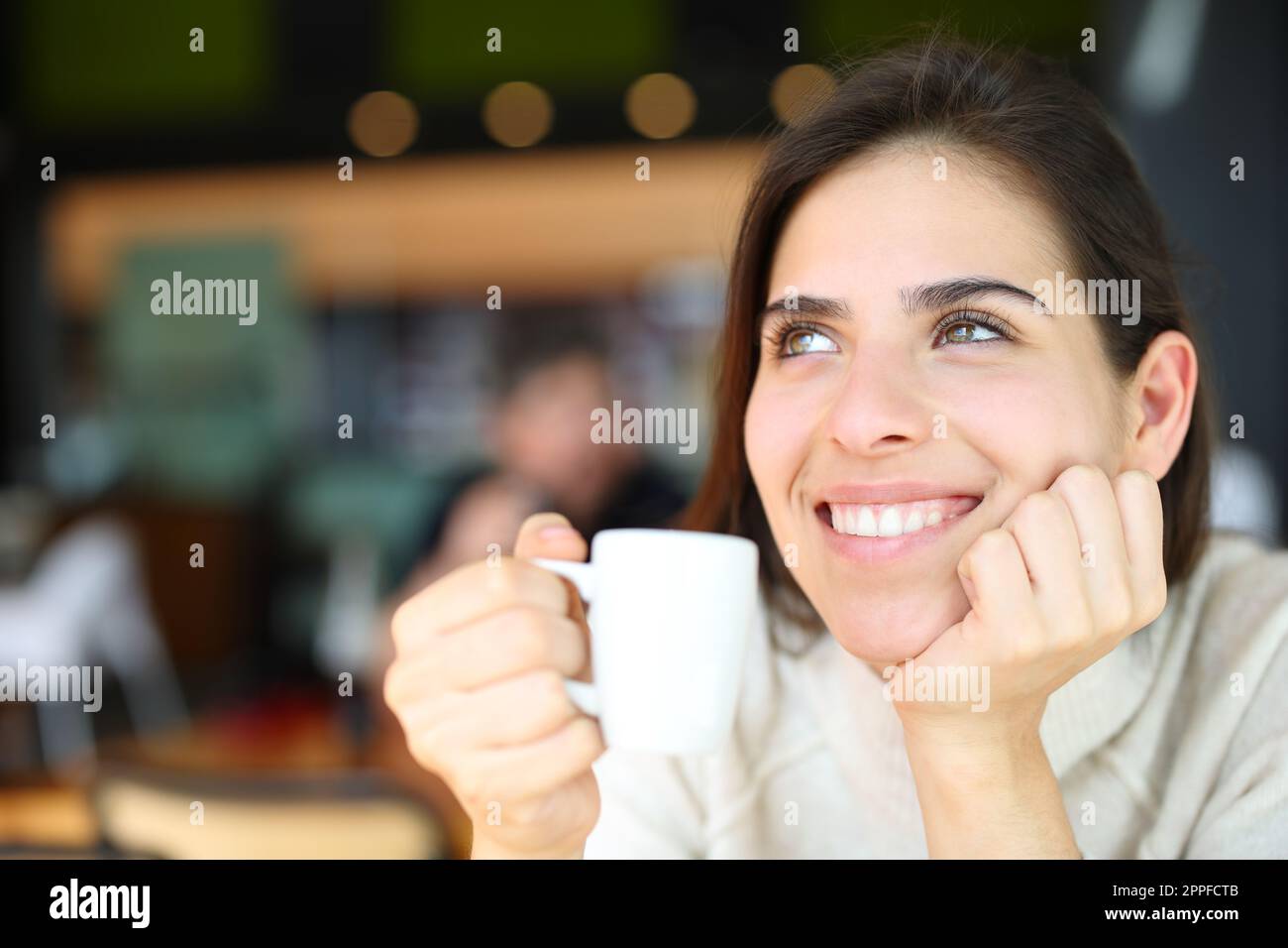 Happy woman dreaming drinking coffee in a restaurant Stock Photo