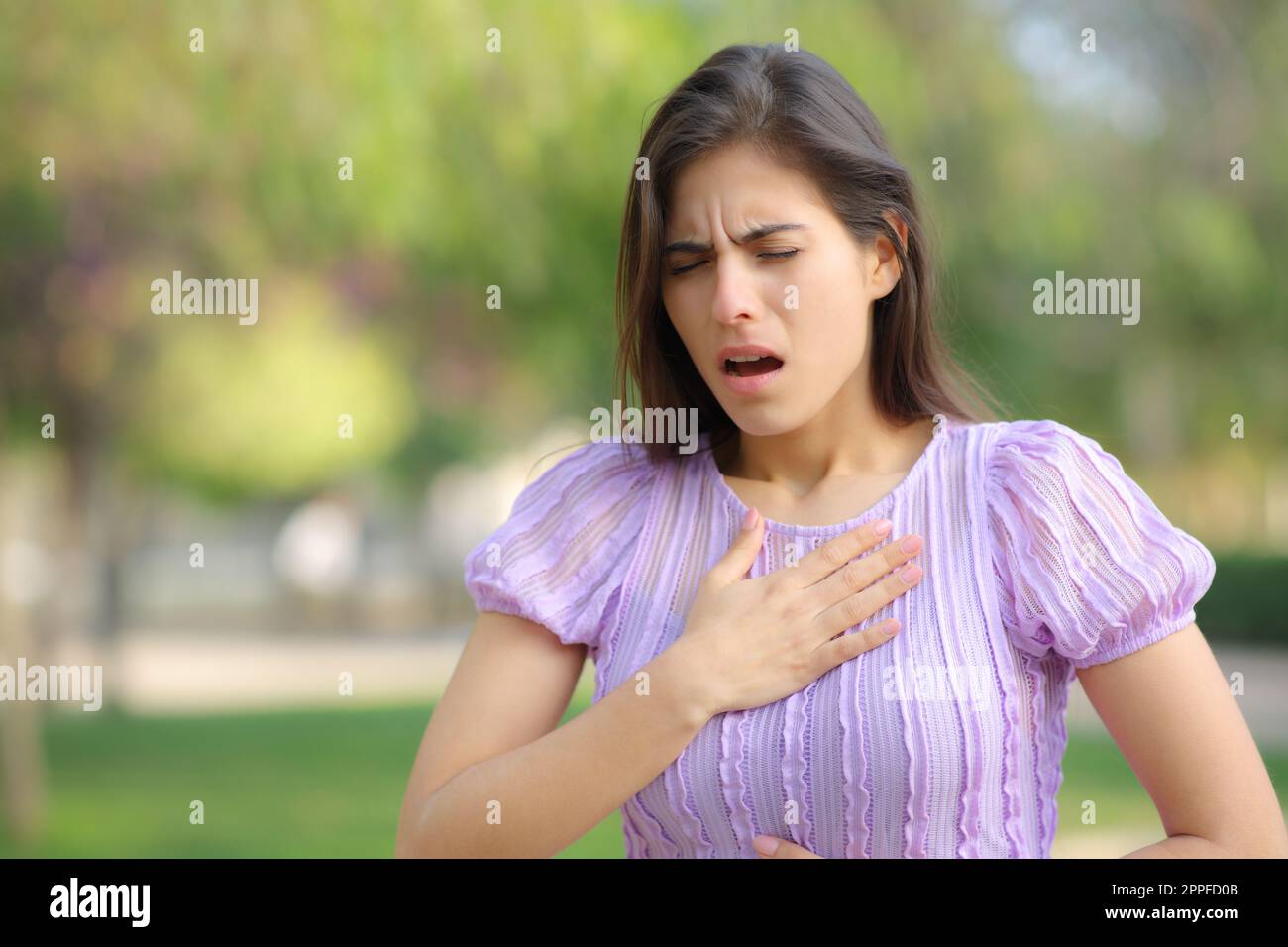 Stressed woman suffering asthma attack in a park Stock Photo