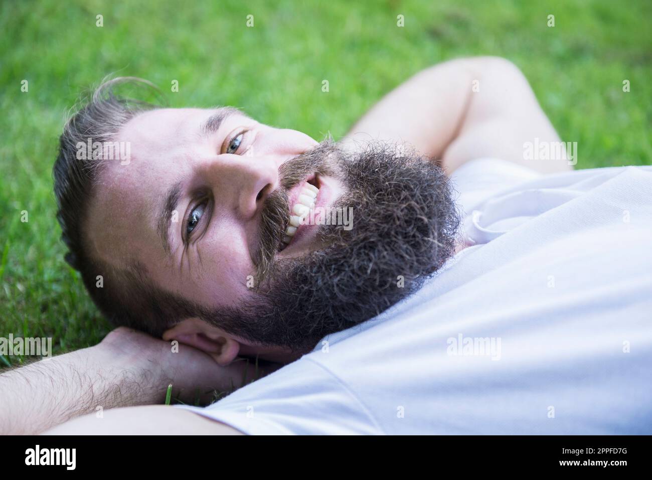 Happy young man lying in garden, Bavaria, Germany Stock Photo