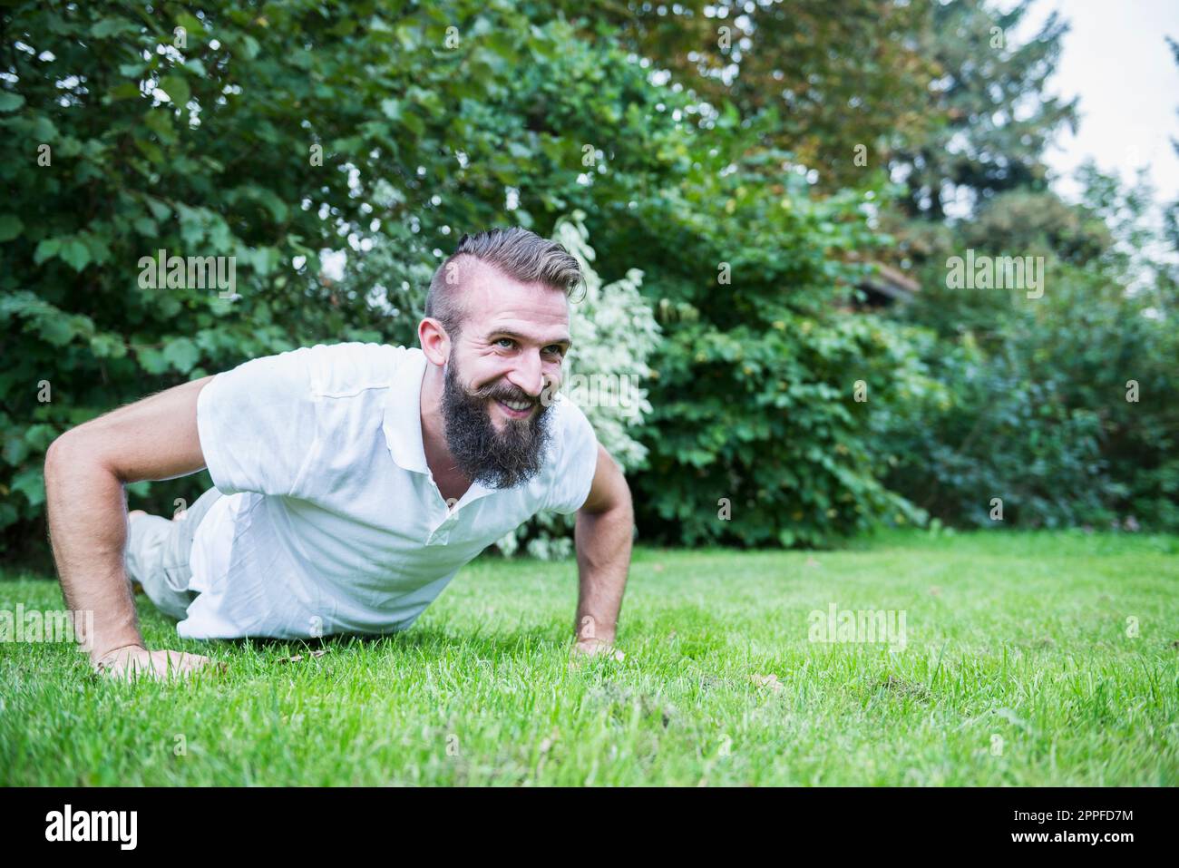 Young man doing push-ups in garden, Bavaria, Germany Stock Photo