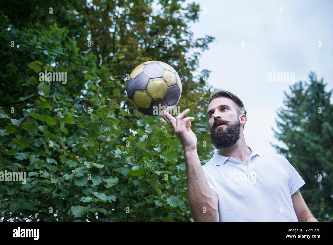 Young man balancing football on finger, Bavaria, Germany Stock Photo