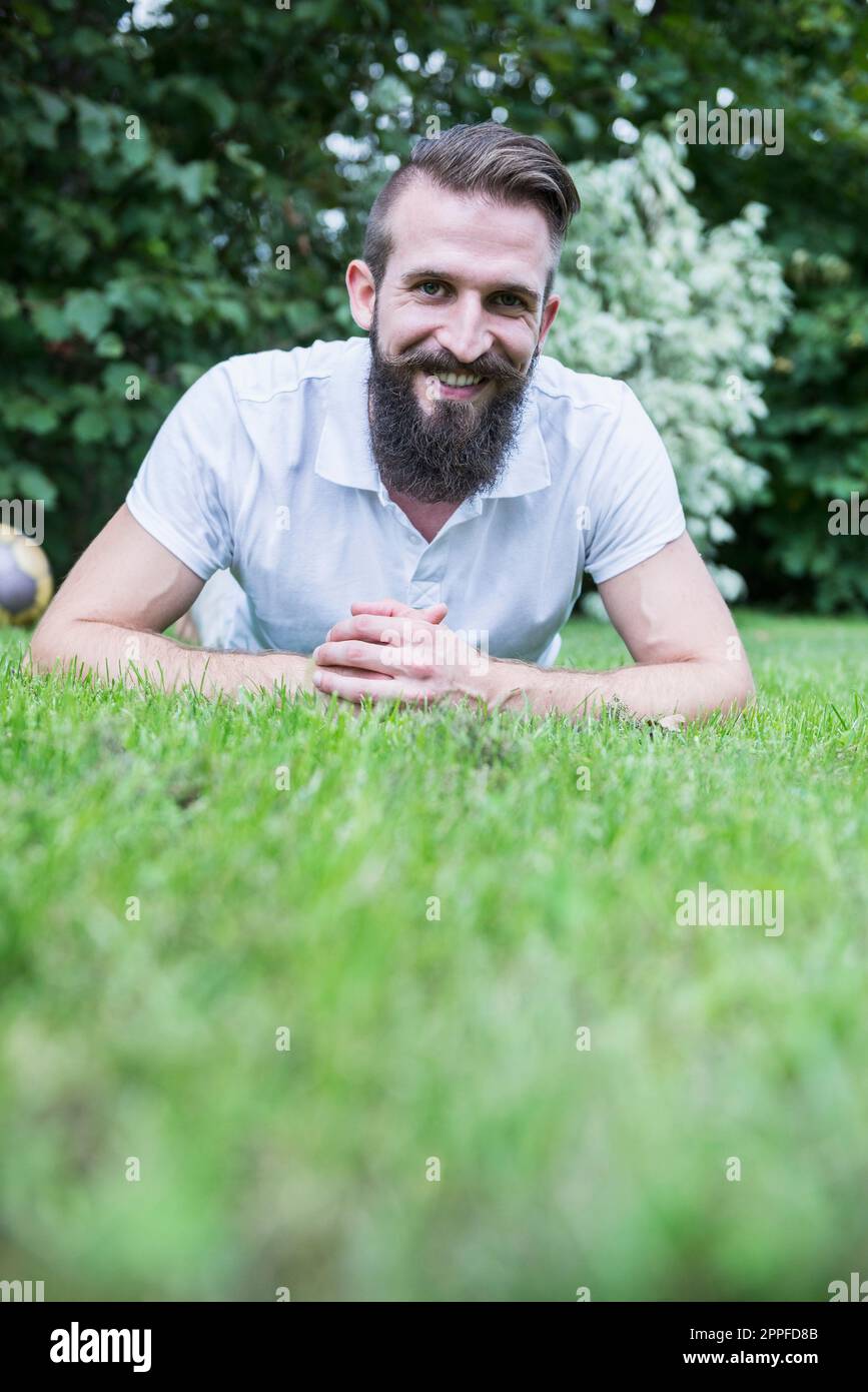 Portrait of a happy young man lying in garden, Bavaria, Germany Stock Photo