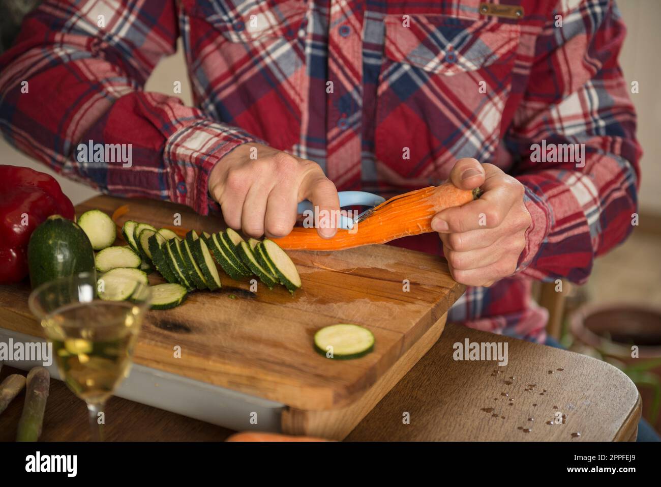 Midsection of a man peeling carrot on chopping board, Munich, Bavaria, Germany Stock Photo