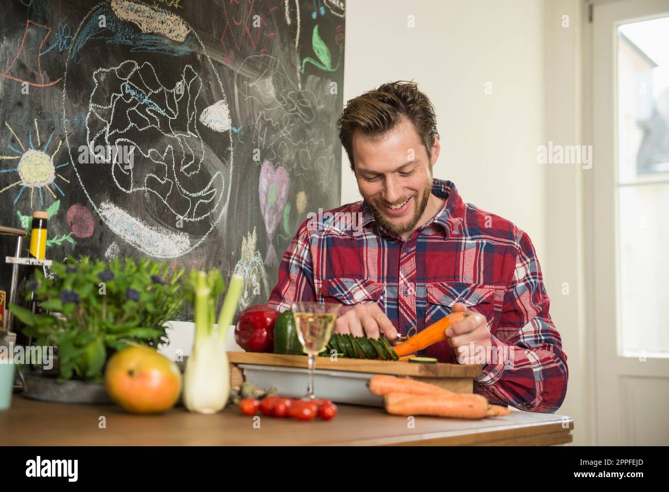 Man peeling carrot on chopping board, Munich, Bavaria, Germany Stock Photo