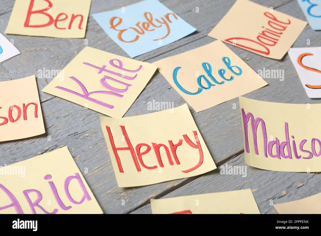 Colorful paper sheets with written different baby names on grey wooden ...