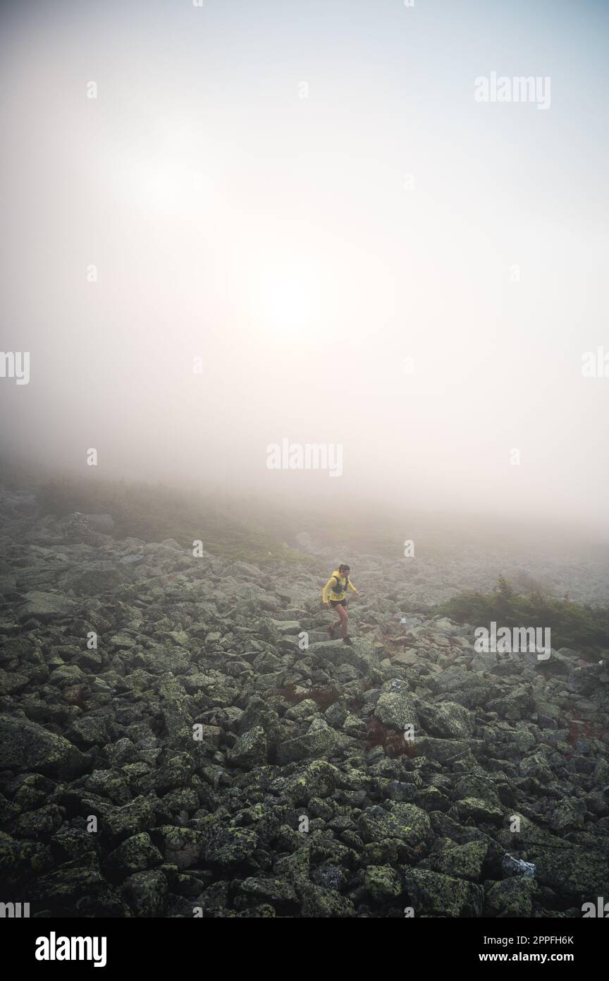 Woman trail running in fog on NH's Presidential Traverse Stock Photo