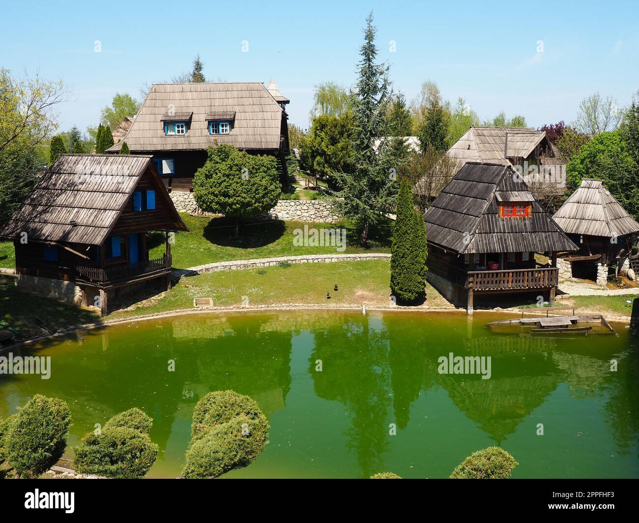 Stanisici, Bijelina, Bosnia and Herzegovina. April 25, 2021 Ethno-village, traditional village houses made of logs, Bosnian style of construction in the highlands. Lake with water.Wooden architecture. Stock Photo