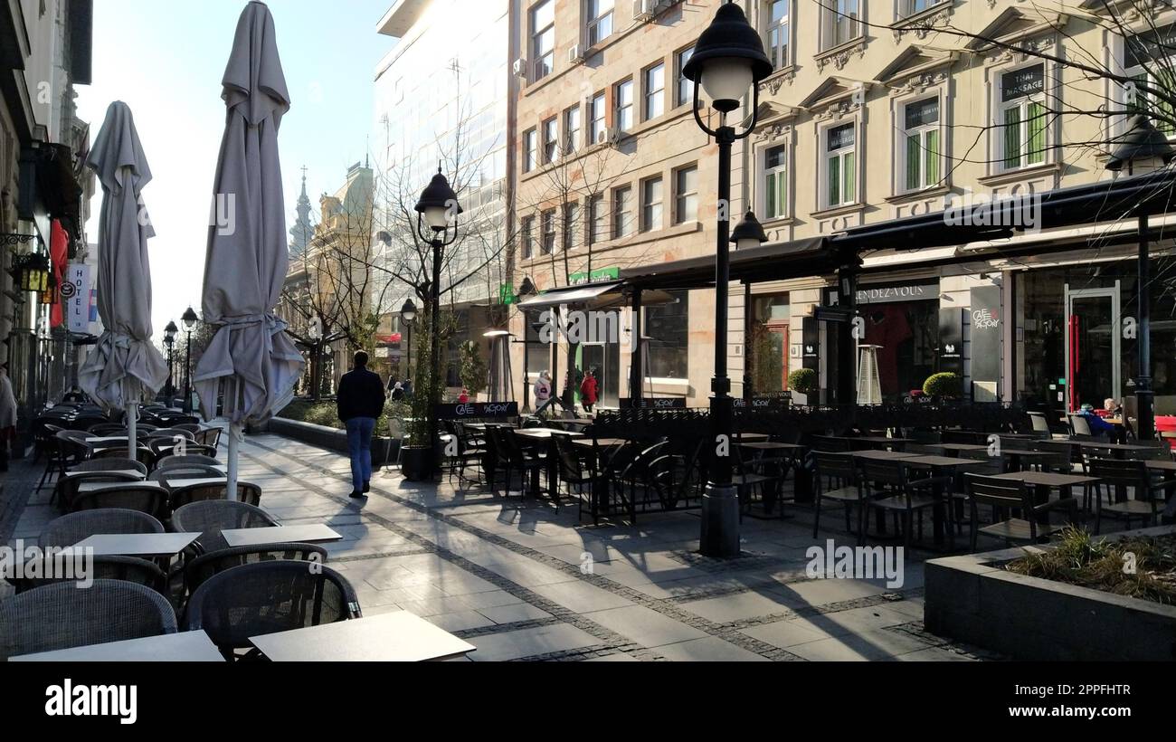 Belgrade, Serbia - January 24, 2020: morning street in the city center. People rush about their business. Street cafes are still closed. Tables, chairs and umbrellas. Passersby go Stock Photo