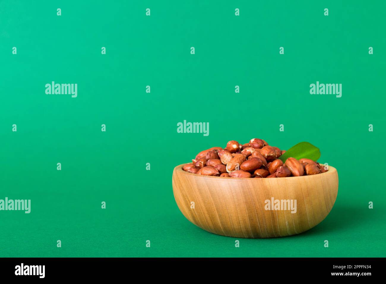 Fresh healthy peanuts in bowl on colored table background. Top view