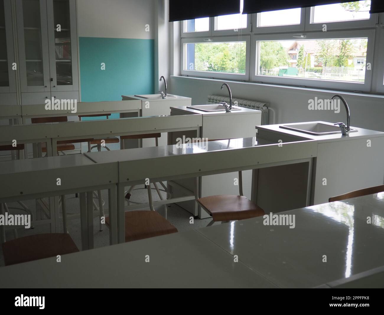 Chemistry room in a modern new school. Beautiful white furniture with sinks and washbasins. Large windows with blackout curtains or blinds. Empty school classroom. Furniture and school equipment Stock Photo