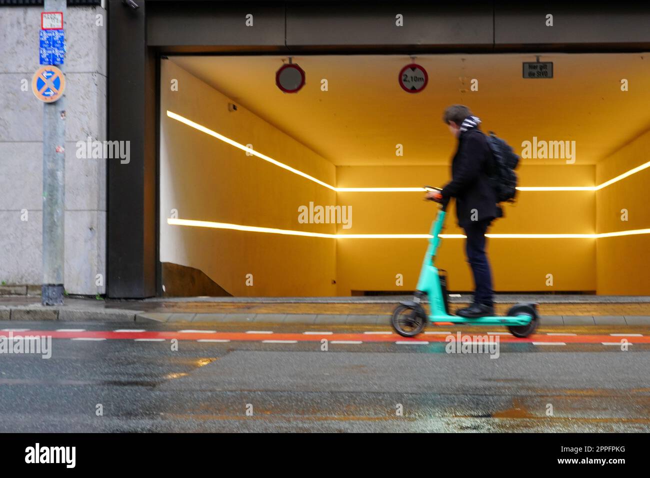 A man with a backpack rides his escooter on a bicycle path past the
