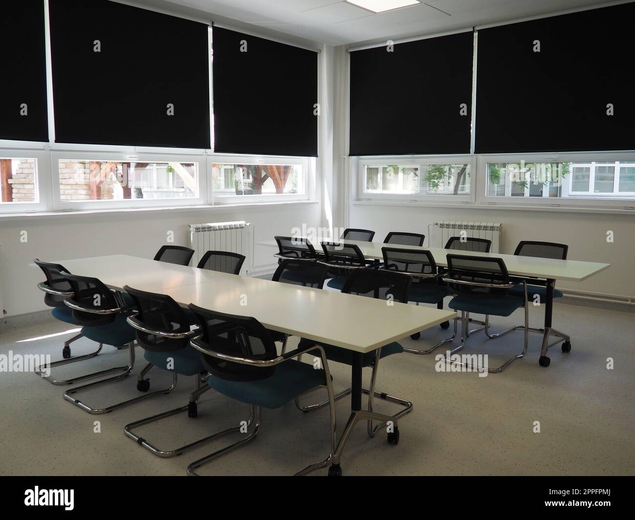 table and chairs in the meeting room in the office, in the classroom or in the library hall. White, black and gray paints in the interior. Black blinds for darkening the room. Modern interior design Stock Photo