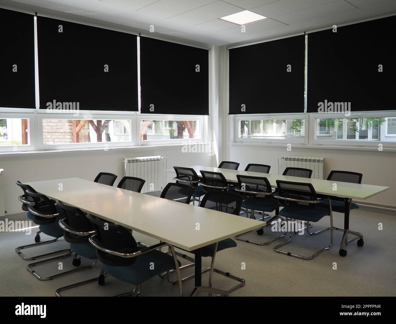table and chairs in the meeting room in the office, in the classroom or in the library hall. White, black and gray paints in the interior. Black blinds for darkening the room. Modern interior design Stock Photo