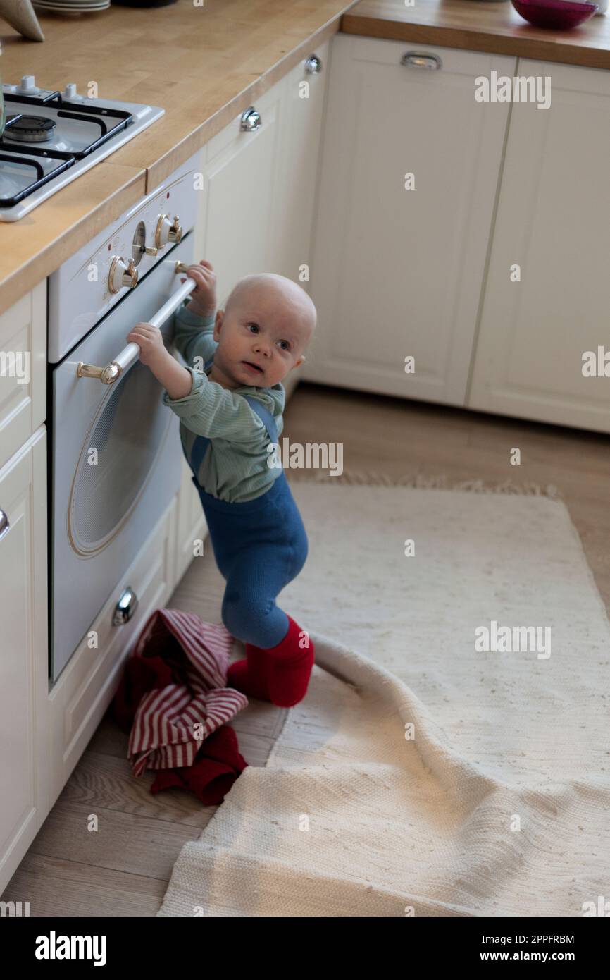 Little boy standing near oven in the kitchen and looks away Stock Photo