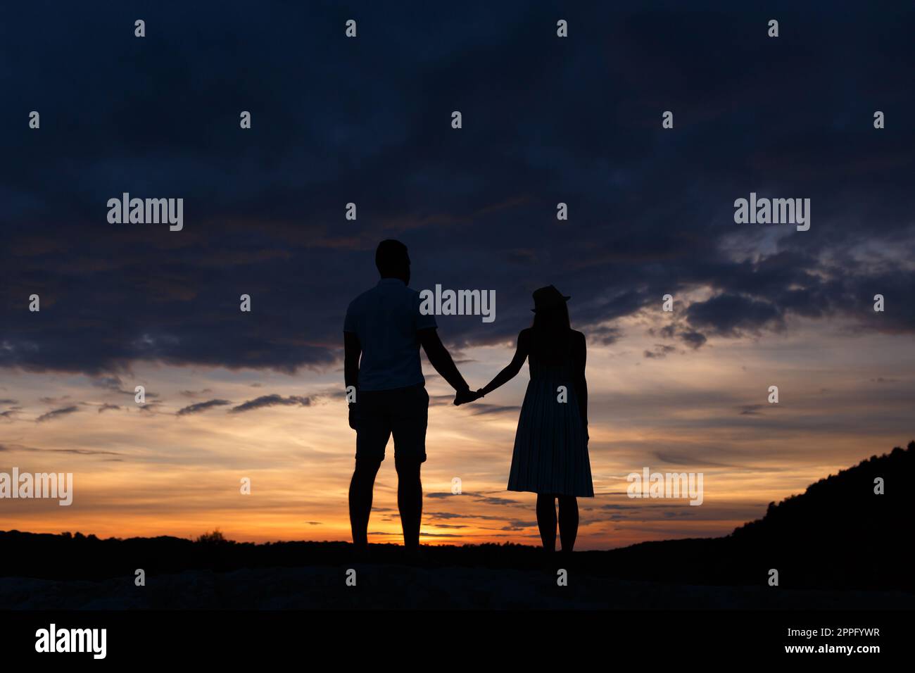 Couple standing holding hands at summer sunset Stock Photo
