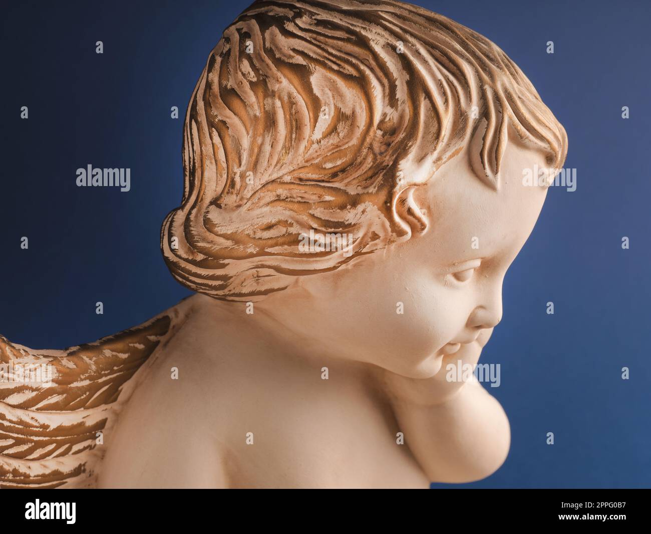 Close up of an angel with golden hair on a blue background Stock Photo