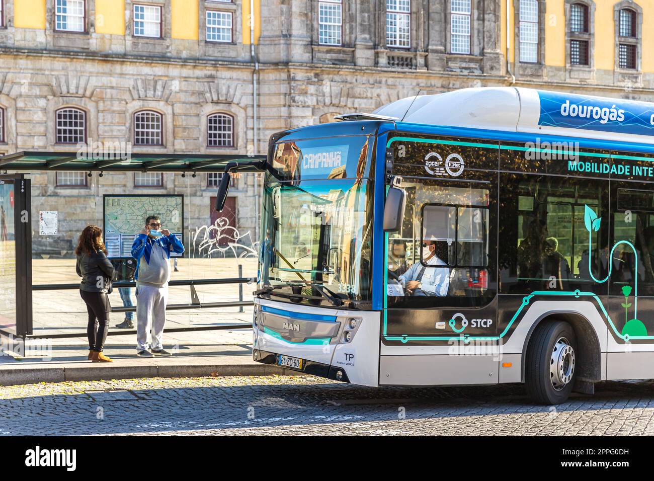 Gas powered bus stopped in a bus stop in front of the Portuguese Electricity and Photography Museum in Porto, Portugal Stock Photo