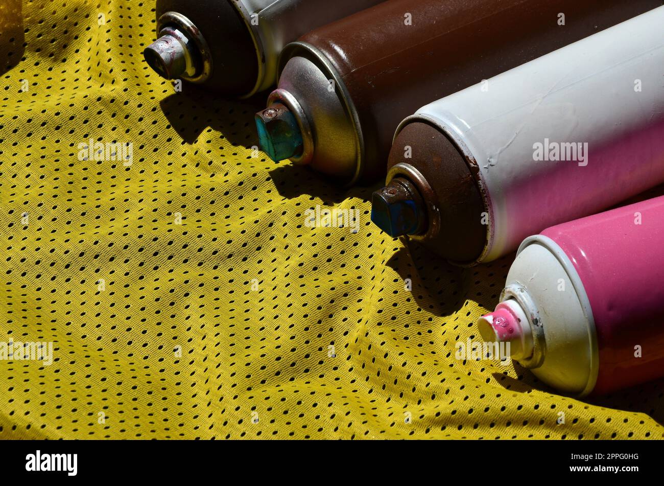 Several used aerosol paint sprayers lie on the sports shirt of a basketball player made of polyester fabric. The concept of youth street art, active sports and eventful lifestyle Stock Photo