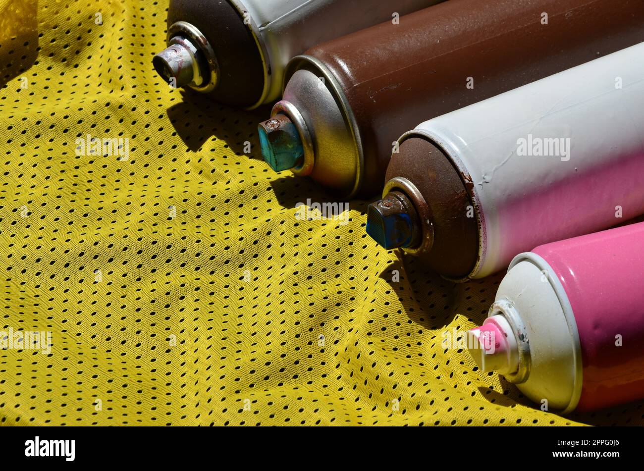 Several used aerosol paint sprayers lie on the sports shirt of a basketball player made of polyester fabric. The concept of youth street art, active sports and eventful lifestyle Stock Photo