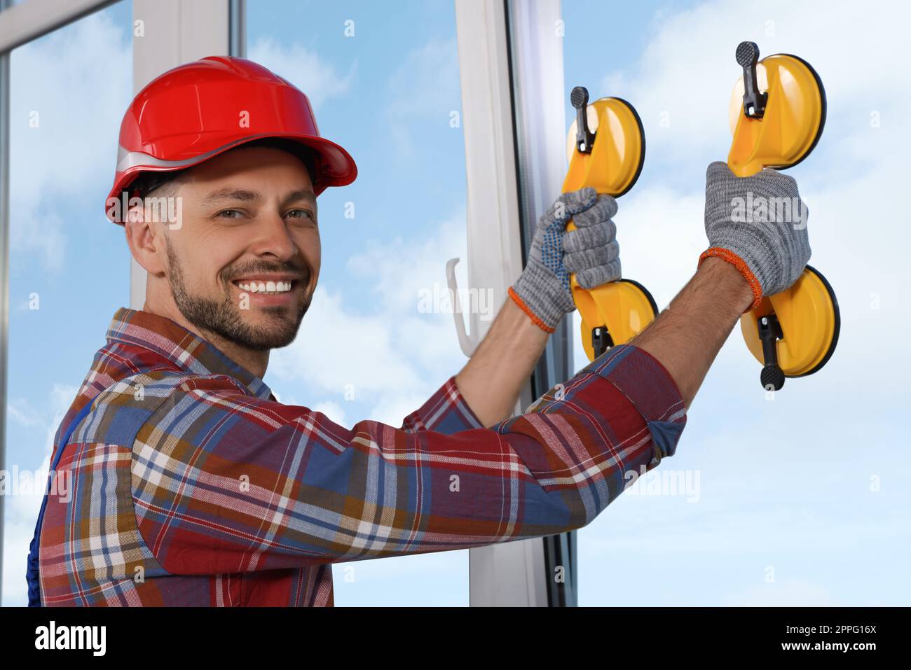 Worker using suction lifters during plastic window installation indoors Stock Photo
