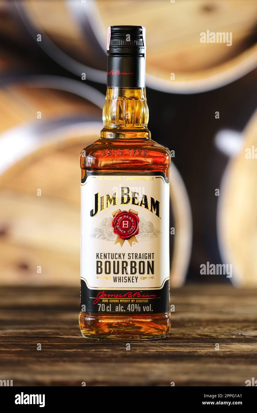 March 28, 2019, Minsk, Belarus - Bottle of kentucky bourbon whiskey on wooden table with barrel on background Stock Photo