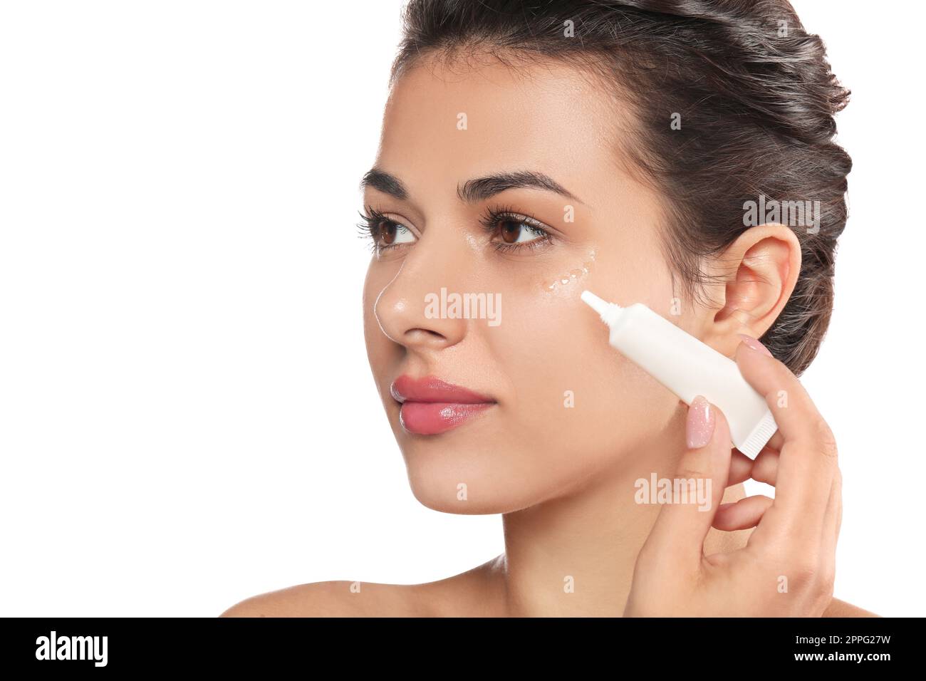 Woman applying cream under eyes on white background, closeup. Skin care