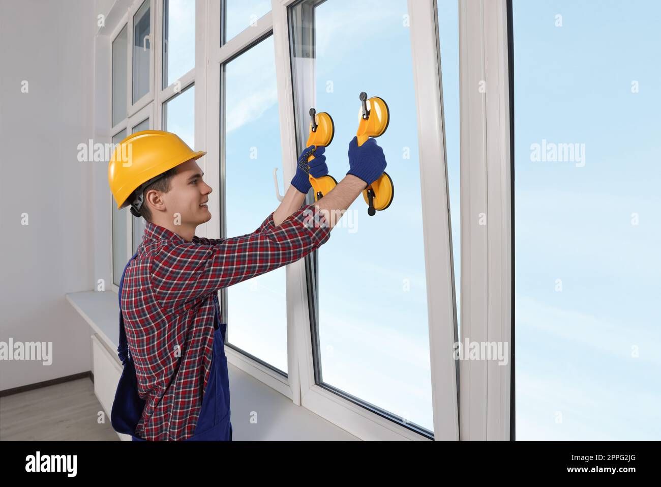 Worker using suction lifters during plastic window installation indoors Stock Photo