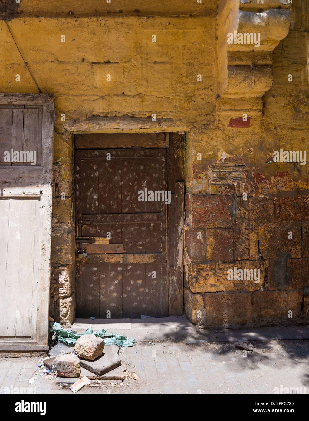 Broken wooden door on orange grunge stone bricks wall in abandoned district Stock Photo
