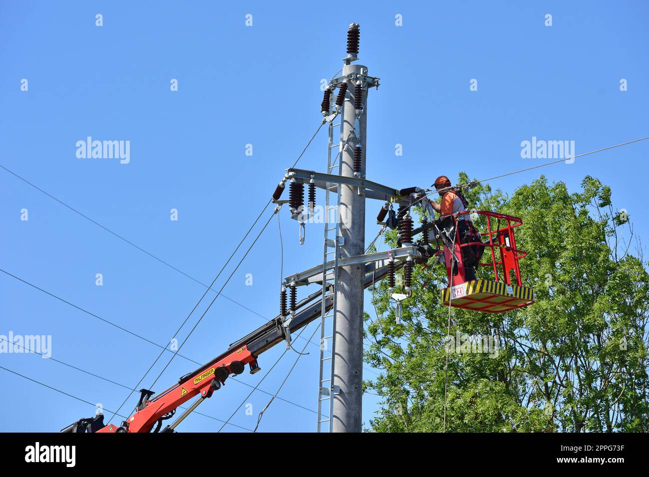 Freileitungsmonteur bei der Arbeit auf einem Strommasten, OberÃ¶sterreich - Worker at work on a power pole, Upper Austria Stock Photo