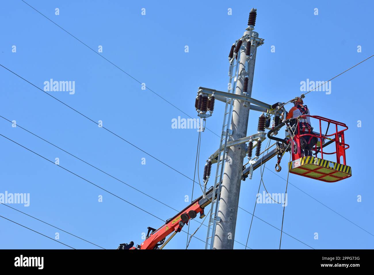 Freileitungsmonteur bei der Arbeit auf einem Strommasten, OberÃ¶sterreich - Worker at work on a power pole, Upper Austria Stock Photo