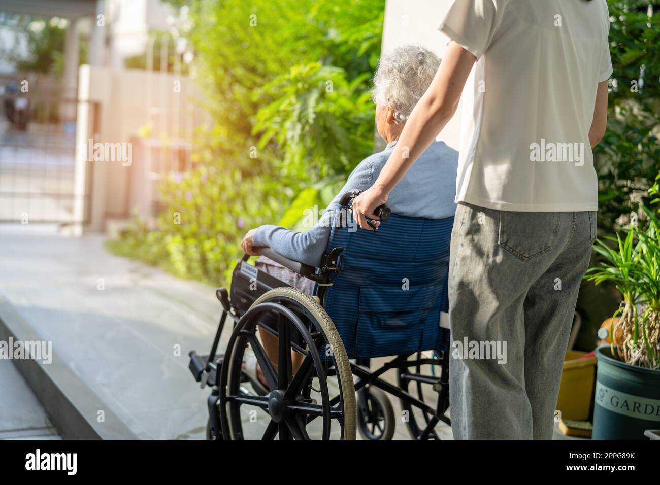 Caregiver help and care Asian senior or elderly old lady woman patient sitting on wheelchair to ramp in nursing hospital, healthy strong medical concept. Stock Photo