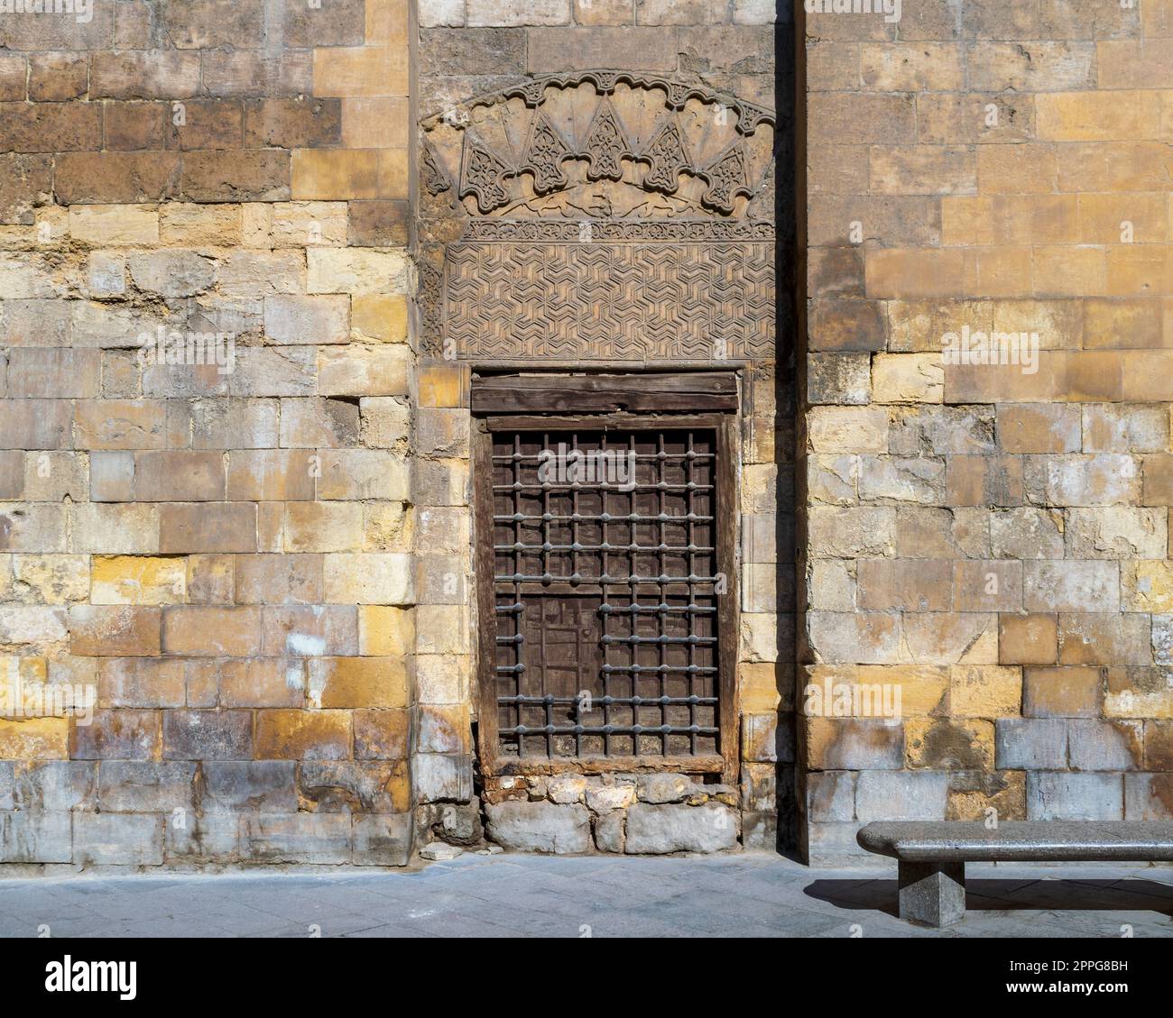 Grunge wooden window with decorated iron grid over stone bricks wall ...