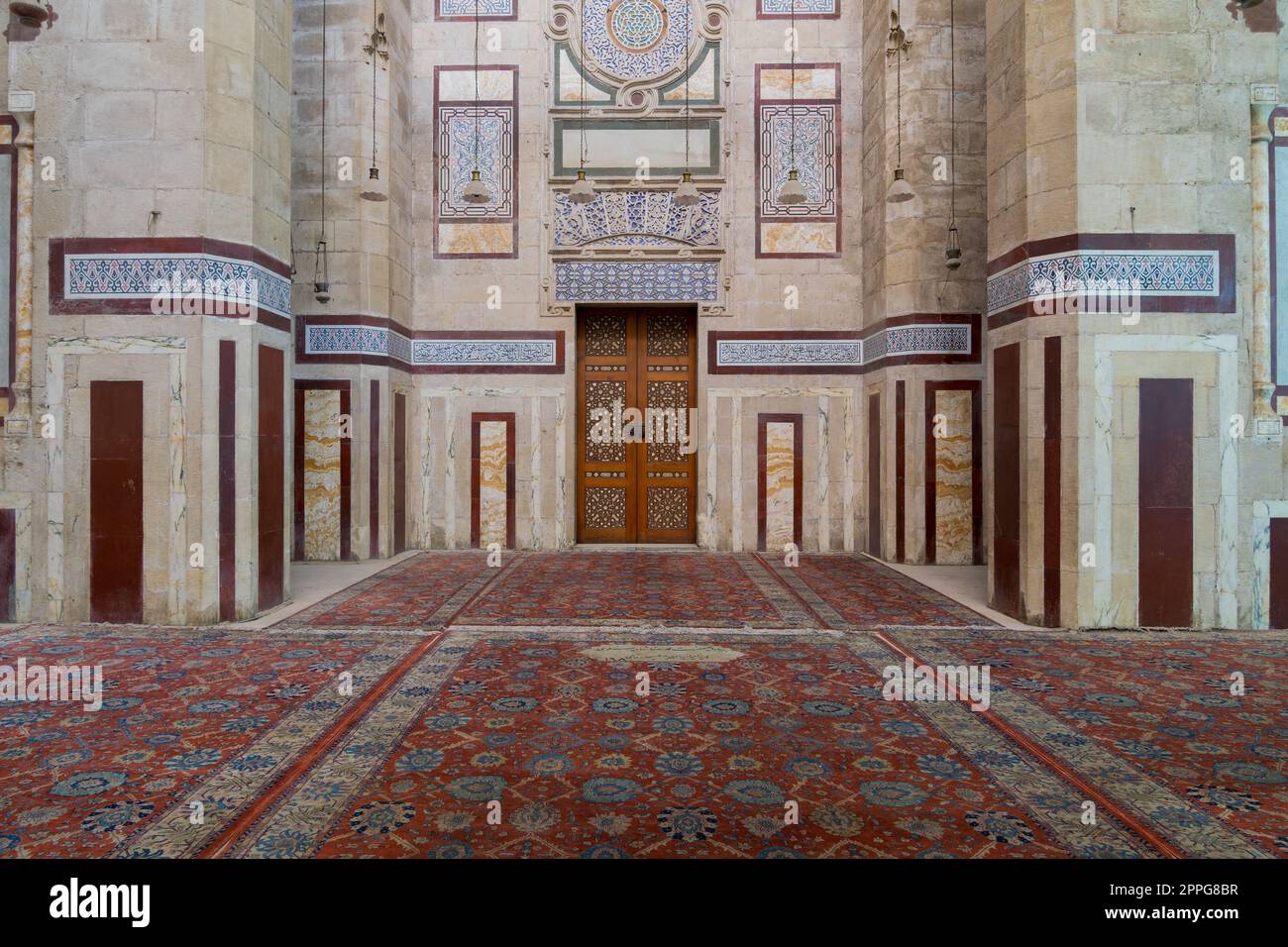 Old decorated stone wall, marble decorations and arabesque decorated wooden door, al Refai Mosque Stock Photo