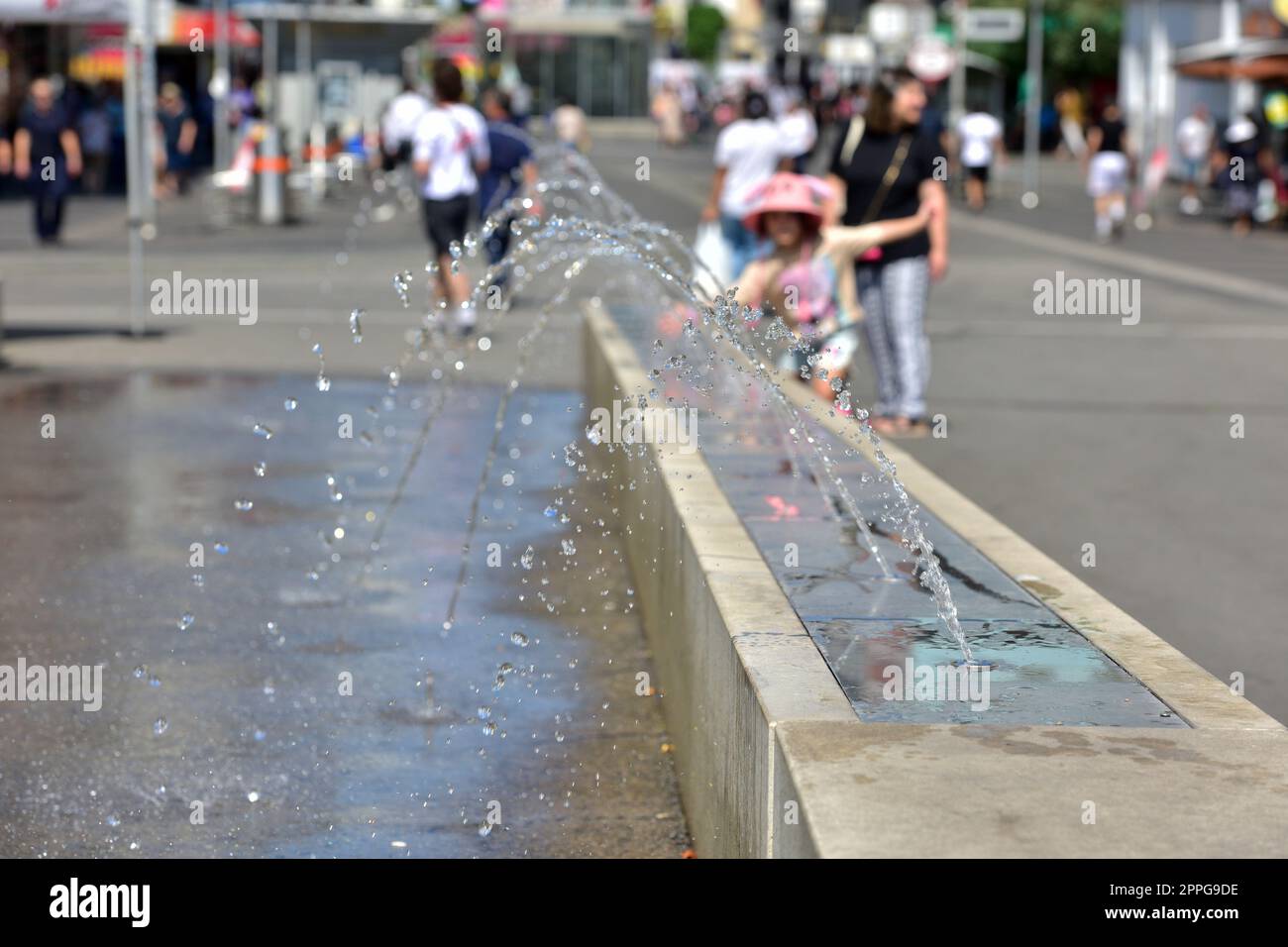 Ein MÃ¤dchen kÃ¼hlt sich an einem Wasserspiel in Wien (Bezirk Favoriten) ab - A girl cools off at a water feature in Vienna (Favoriten district) Stock Photo