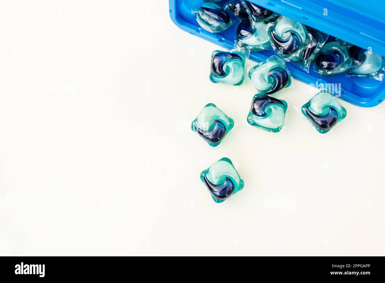 Blue-and-blue washing capsules are scattered on a white background. The process of washing clothes. Liquid washing gel. Stock Photo