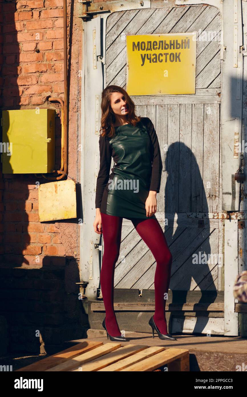 Fashion model posing near factory door with warning plate. Stock Photo