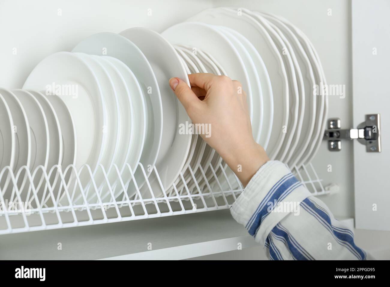 Woman taking ceramic plate from drying rack, closeup Stock Photo