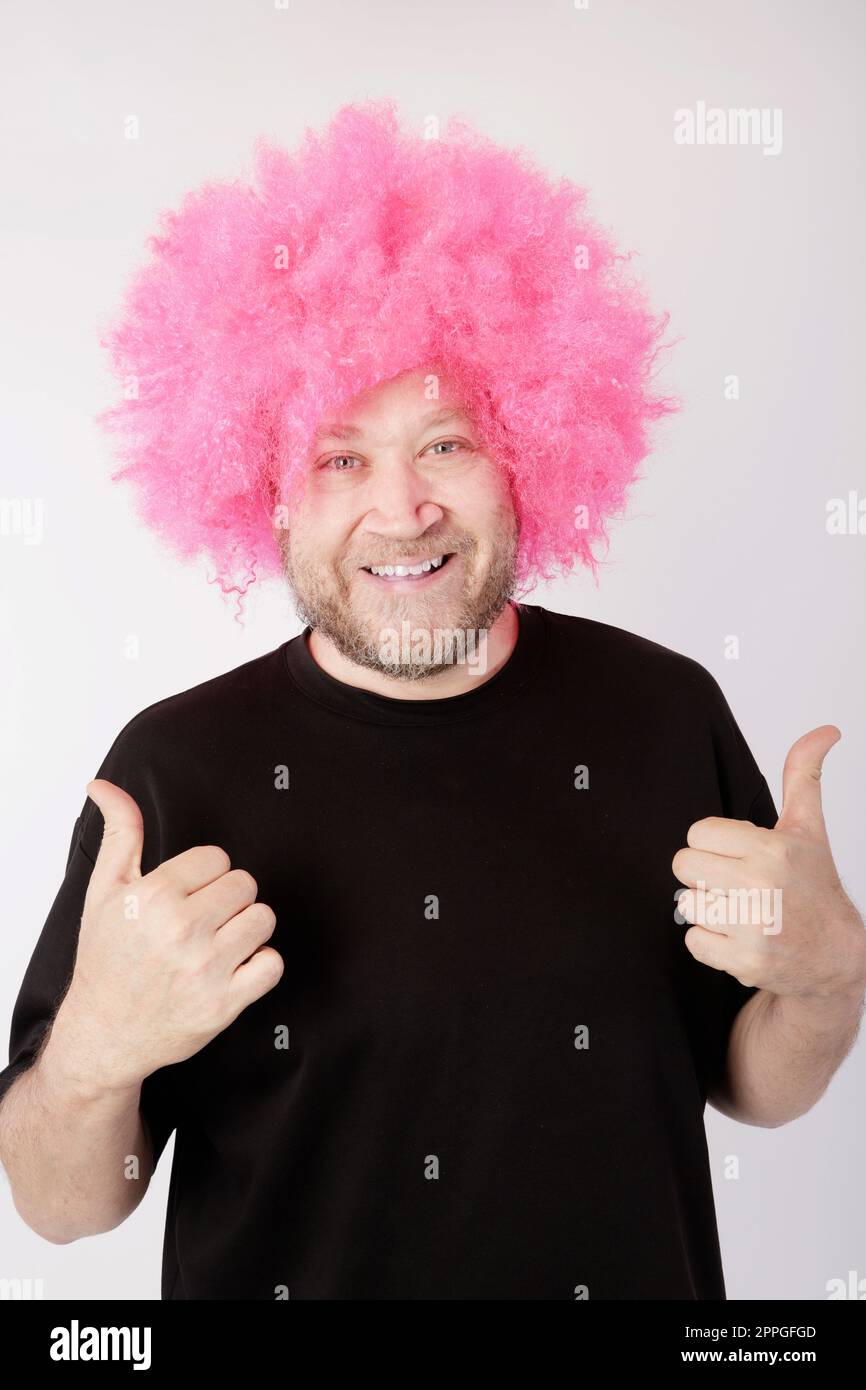 smiling man with pink afro wig Stock Photo
