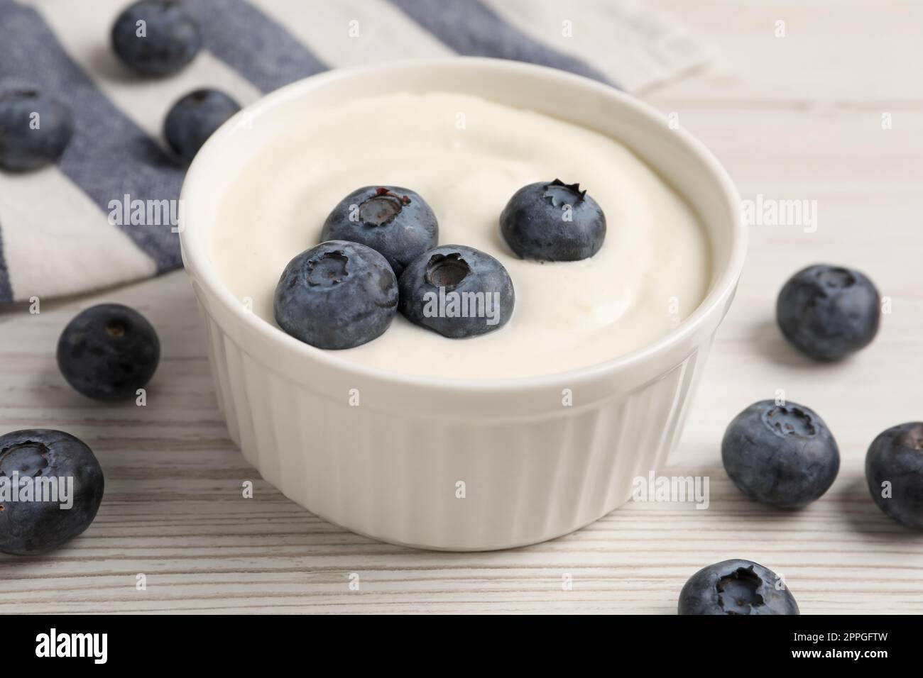 Bowl of yogurt with blueberries served on white wooden table Stock Photo